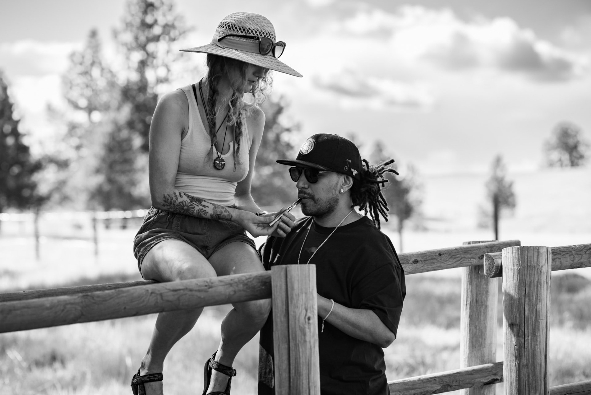 Two friends on a ranch fence sharing a Vuber vaporizer
