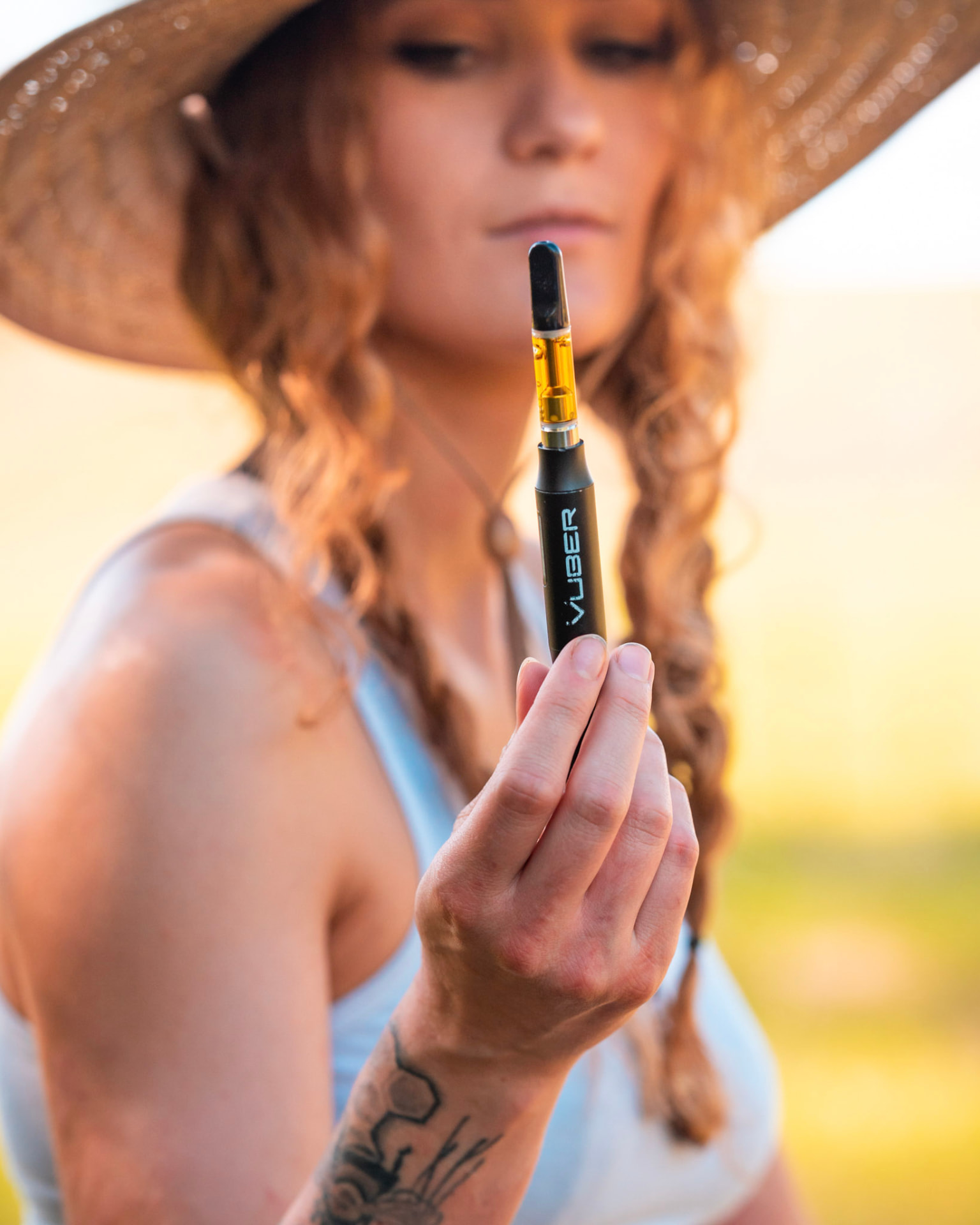 Woman in a straw hat holding a Vuber battery with a full quartz cartridge
