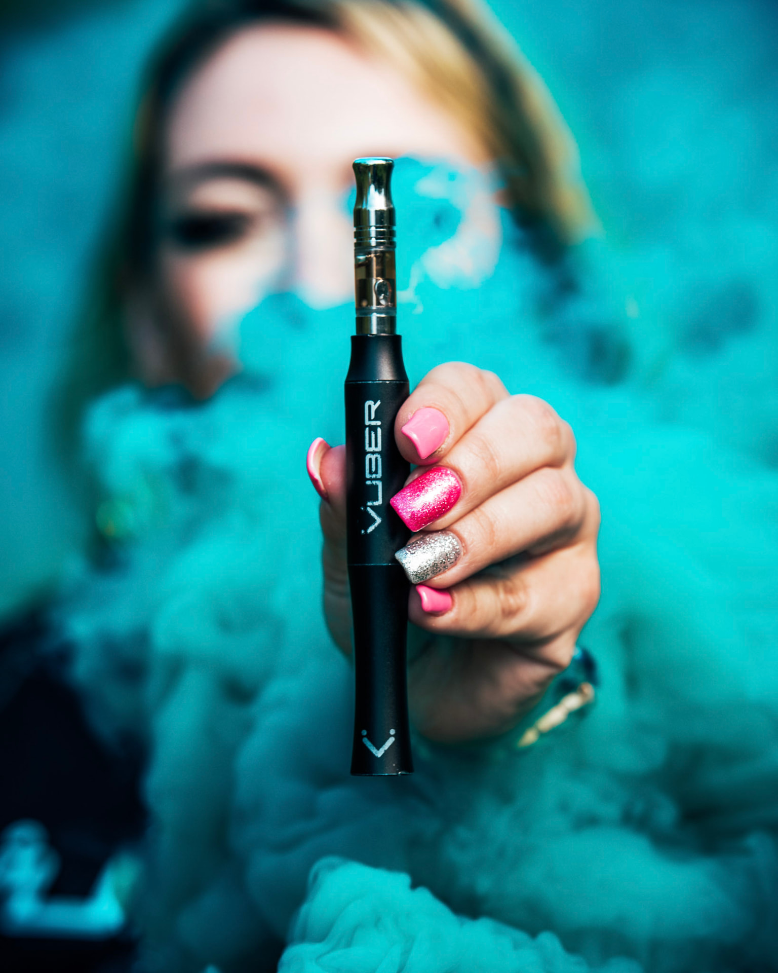 Hand holding a Vuber Pulse smart battery with a quartz cartridge in teal vapor